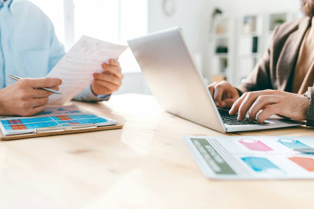 Contemporary male analysts working with electronic and paper financial documents