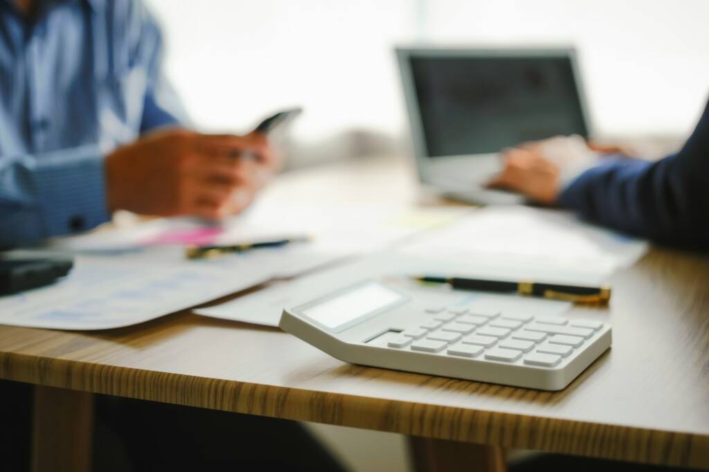 Desk-bound businessman calculates figures, verified accounts, and collaborates in discussions.