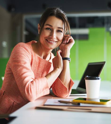 Pretty Caucasian business lady in formal wear leaning on her hands while sitting at the work desk in the meeting room